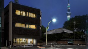 A modern building with a brick facade and large windows, a street lamp, and a tower in the background. - Fukuwauchi (Tokyo)