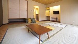A traditional Japanese room with tatami flooring, a low wooden table, a television, and a sliding door closet. - Fukuwauchi (Tokyo)