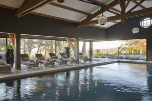 An indoor swimming pool with lounge chairs and potted plants. - Château Saint Pierre de Serjac (Puissalicon)