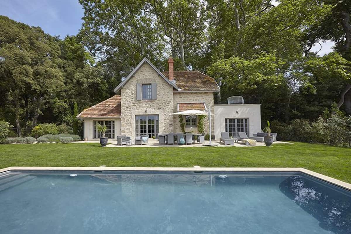 A stone house with a swimming pool, outdoor seating, and a well-maintained lawn.
