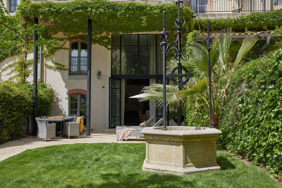 A courtyard with a stone fountain, outdoor seating, and lush greenery.