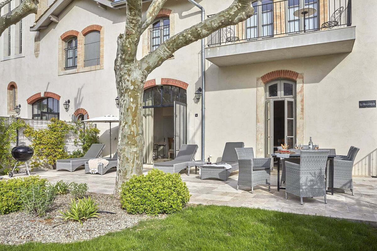 A patio area with outdoor furniture, a barbecue grill, and a well-maintained garden.