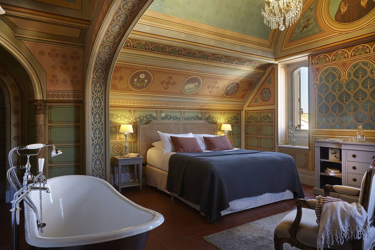 A luxurious bedroom with a large bed, a bathtub, and ornate ceiling decorations.