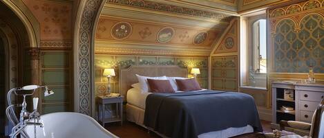 A luxurious bedroom with a large bed, a bathtub, and ornate ceiling decorations.