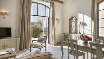 A spacious living room with a large window, a television, a dining table with chairs, and a sofa.