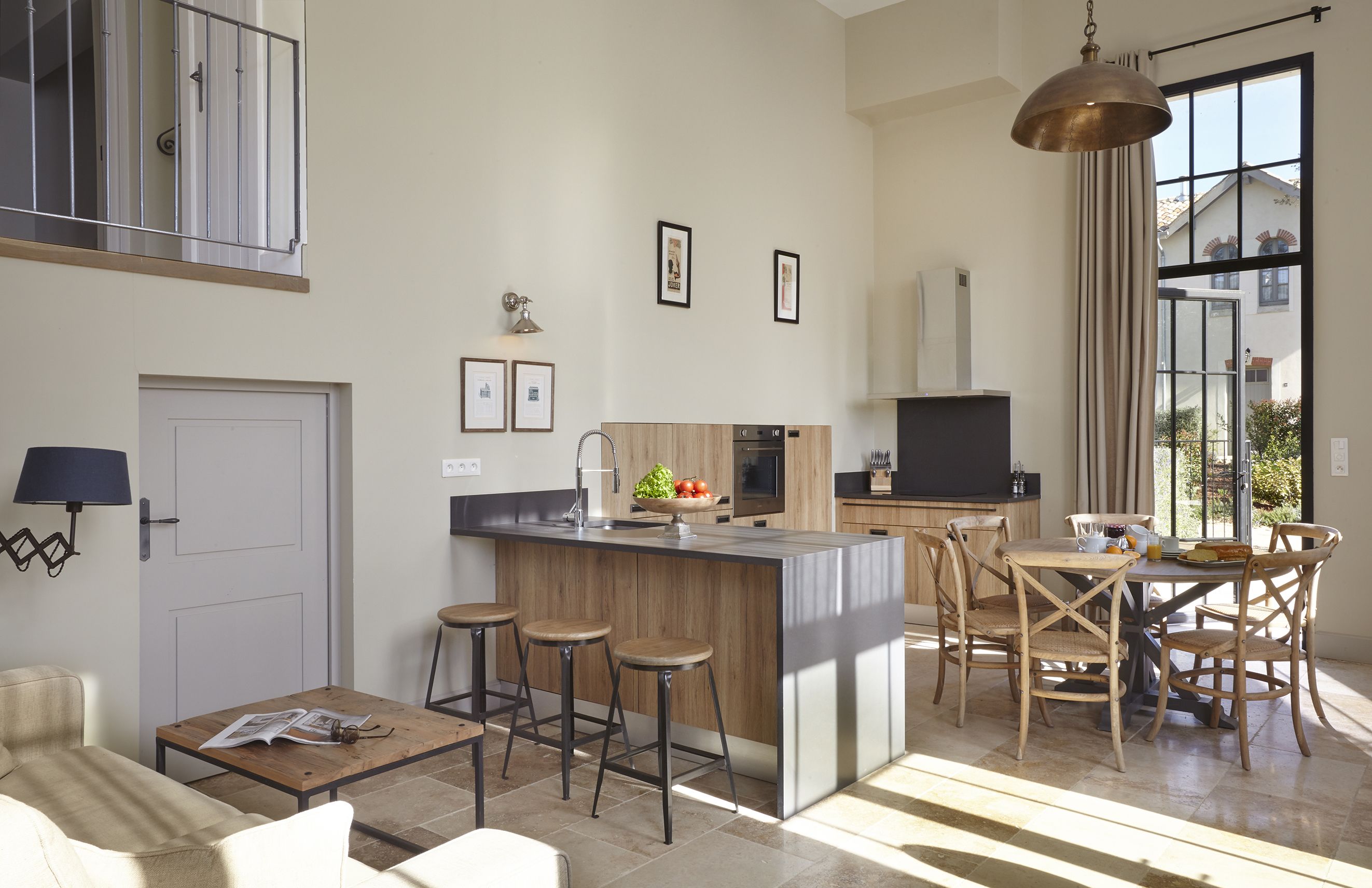 A modern kitchen with a central island, bar stools, and a dining area with wooden chairs.