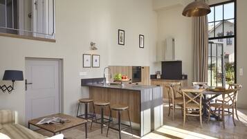 A modern kitchen with a central island, bar stools, and a dining area with wooden chairs.