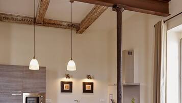 Une cuisine moderne dotée d’un îlot central, de luminaires suspendus et de poutres apparentes en bois.