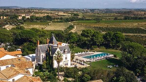 Una extensa propiedad con piscina, campos de viñedos y arquitectura tradicional.