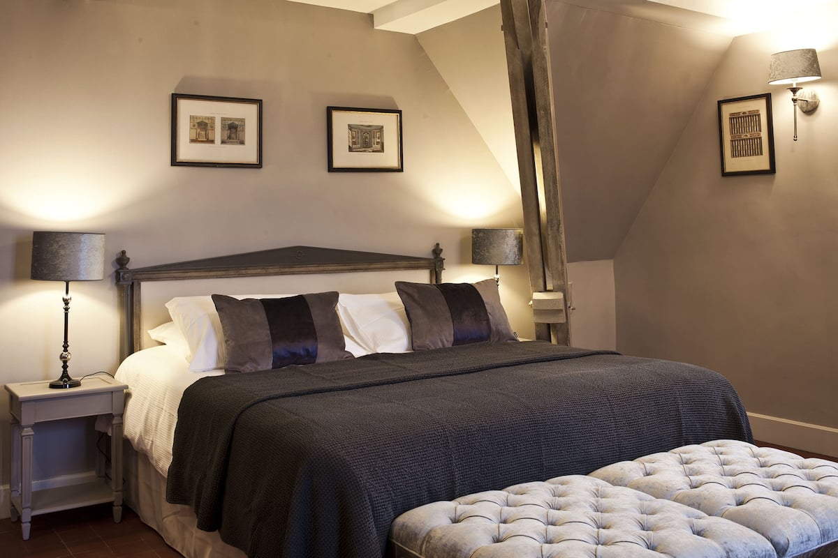 A bedroom with a large bed, a nightstand, a lamp, and two framed pictures on the wall.