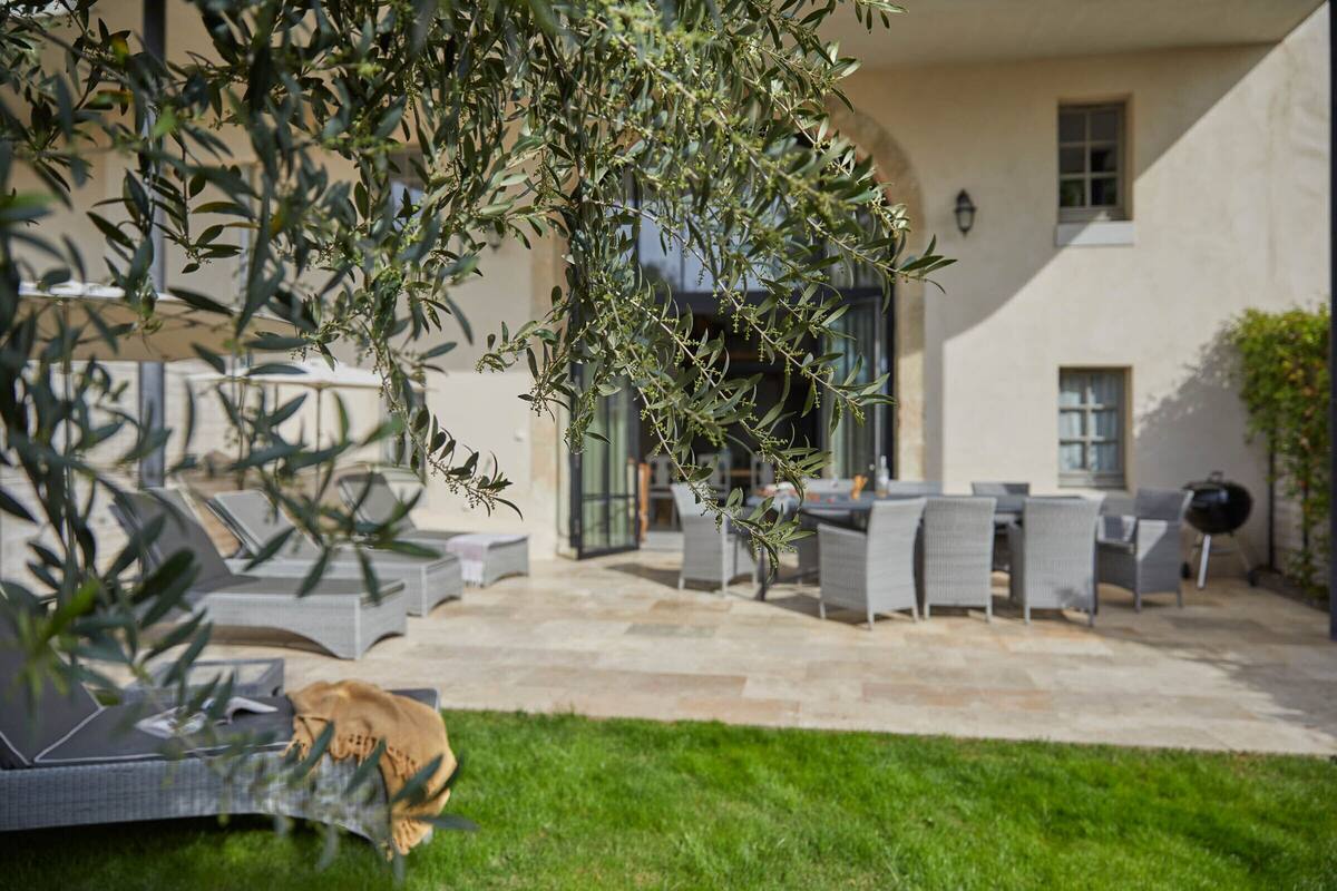 A patio with outdoor furniture, a grassy area, and a building with a stone facade.