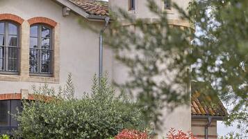 Un bâtiment doté d’une tour ronde, de fenêtres en arc et d’un toit recouvert de tuiles.