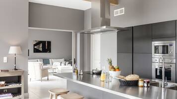 Une cuisine moderne dotée d’un îlot central, d’appareils électroménagers en acier inoxydable et d’un design minimaliste.