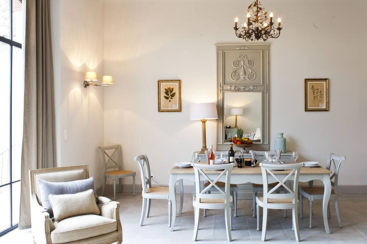 A dining area with a chandelier, a large mirror, and framed artwork on the walls.