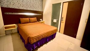 A bedroom with a bed, nightstand, and a wardrobe. - Atreya Hotel Makassar (Makassar)