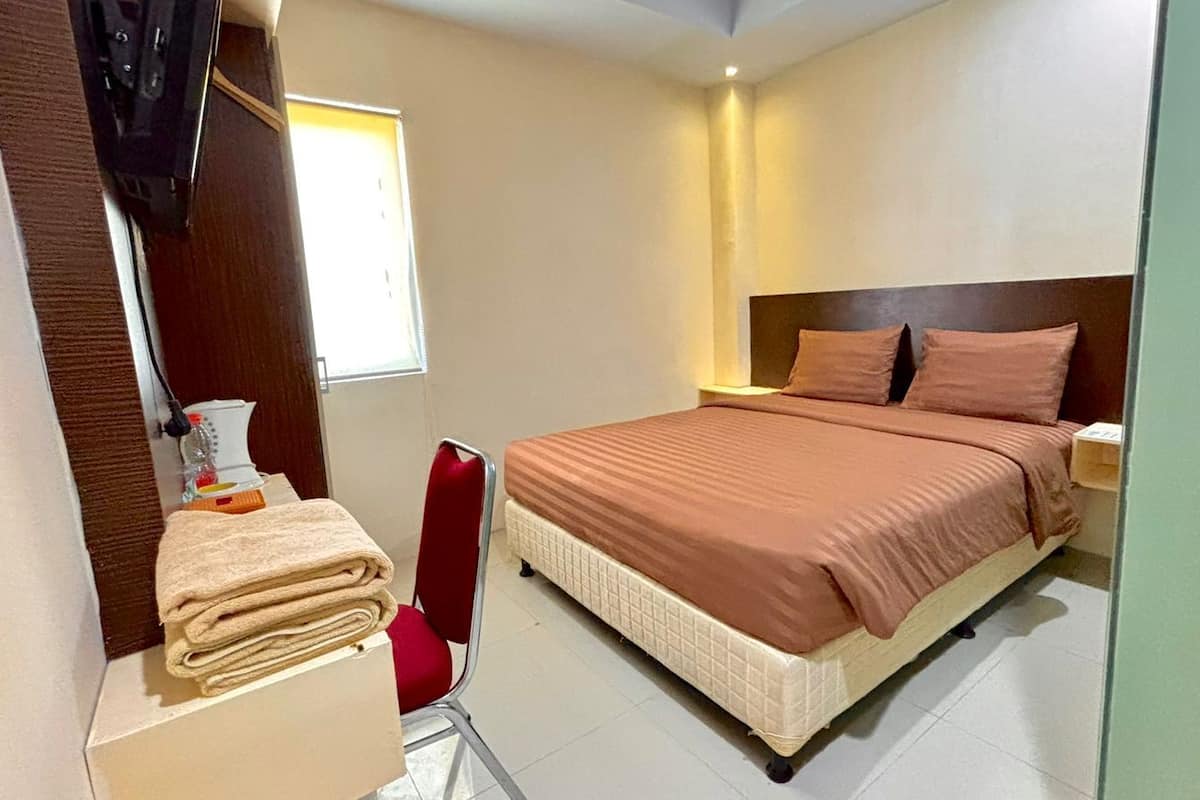Une chambre à coucher avec un lit, une chaise, une table de chevet et une fenêtre.