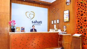 Una recepción en el Hotel Sahati Jakarta con un diseño moderno, un logo con forma de corazón y certificados enmarcados en la pared.