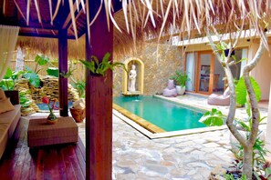 A pool area with stone flooring, a statue, and various plants. - Atman Villas (Ubud)
