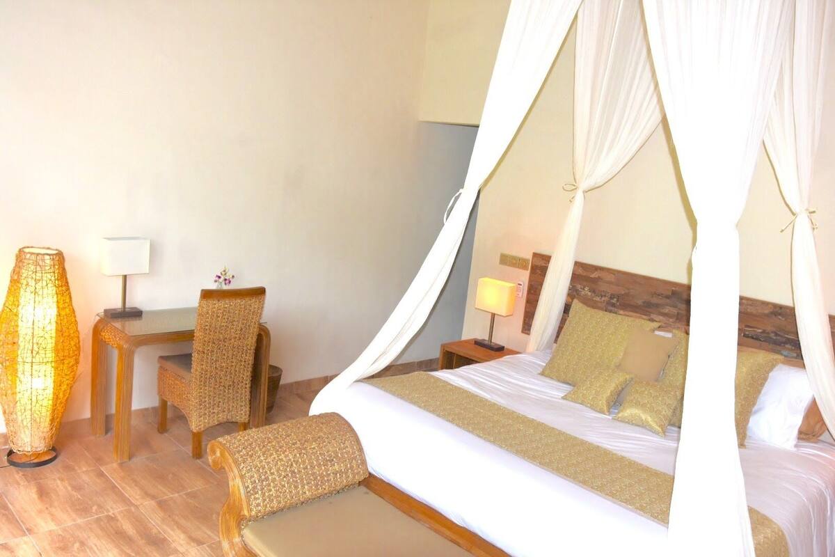 Une chambre d’hôtel avec un lit, une chaise, un bureau et une lampe.