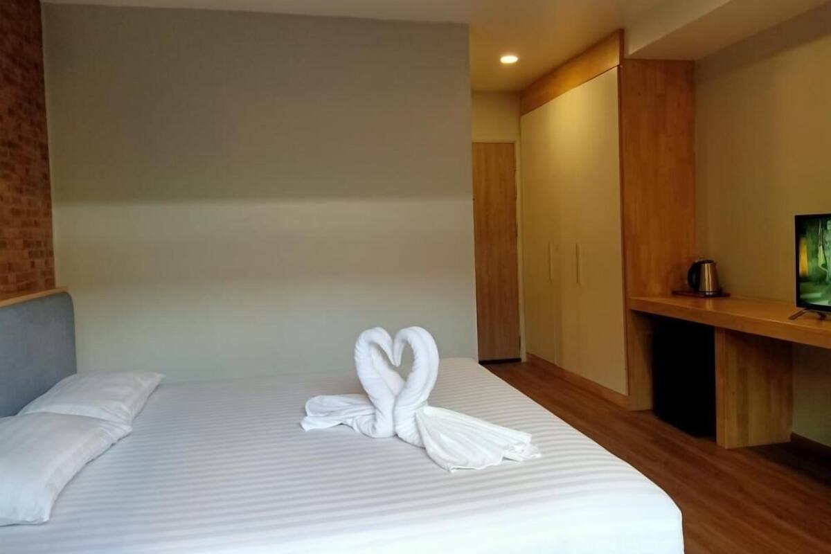 Una habitación de hotel con una cama bien hecha, un televisor sobre un mueble de madera y un armario de madera.