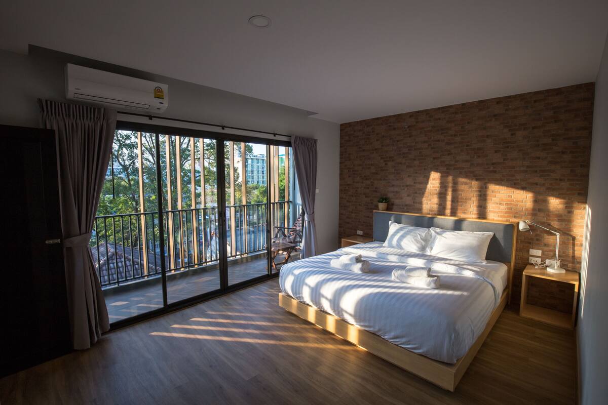 Un dormitorio moderno con una cama grande, una mesita de noche, una ventana con cortinas y vistas al exterior.