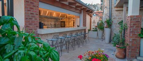 Un patio con mobiliario exterior, una cocina con mostrador integrado y plantas en macetas.