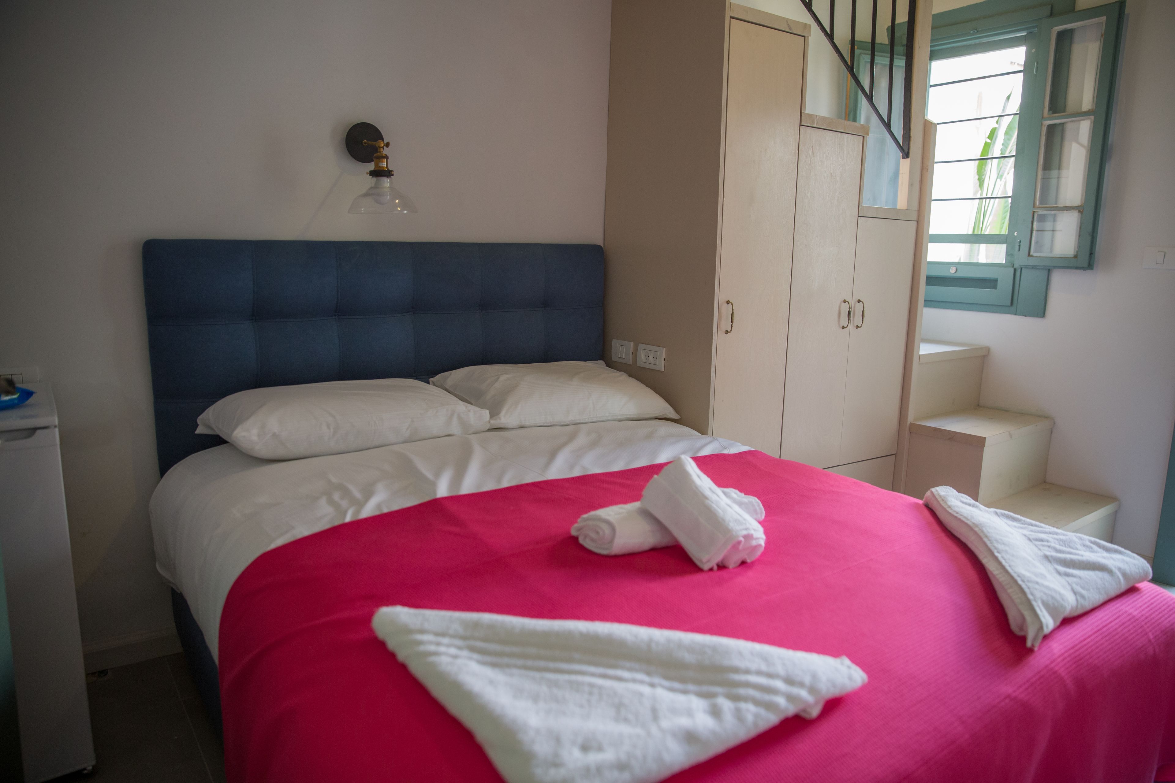 A bedroom with a bed, a wardrobe, a nightstand, and a window with a view.