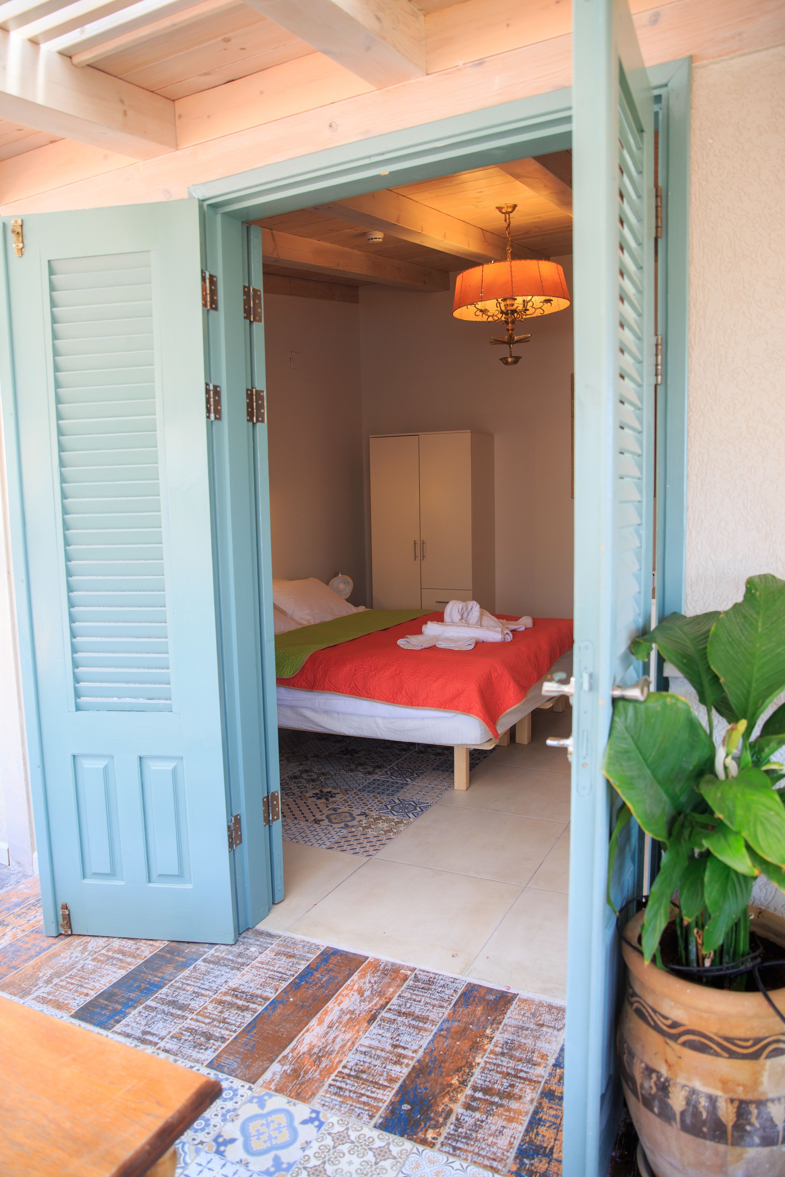 Una habitación con cama, armario y una planta en maceta.