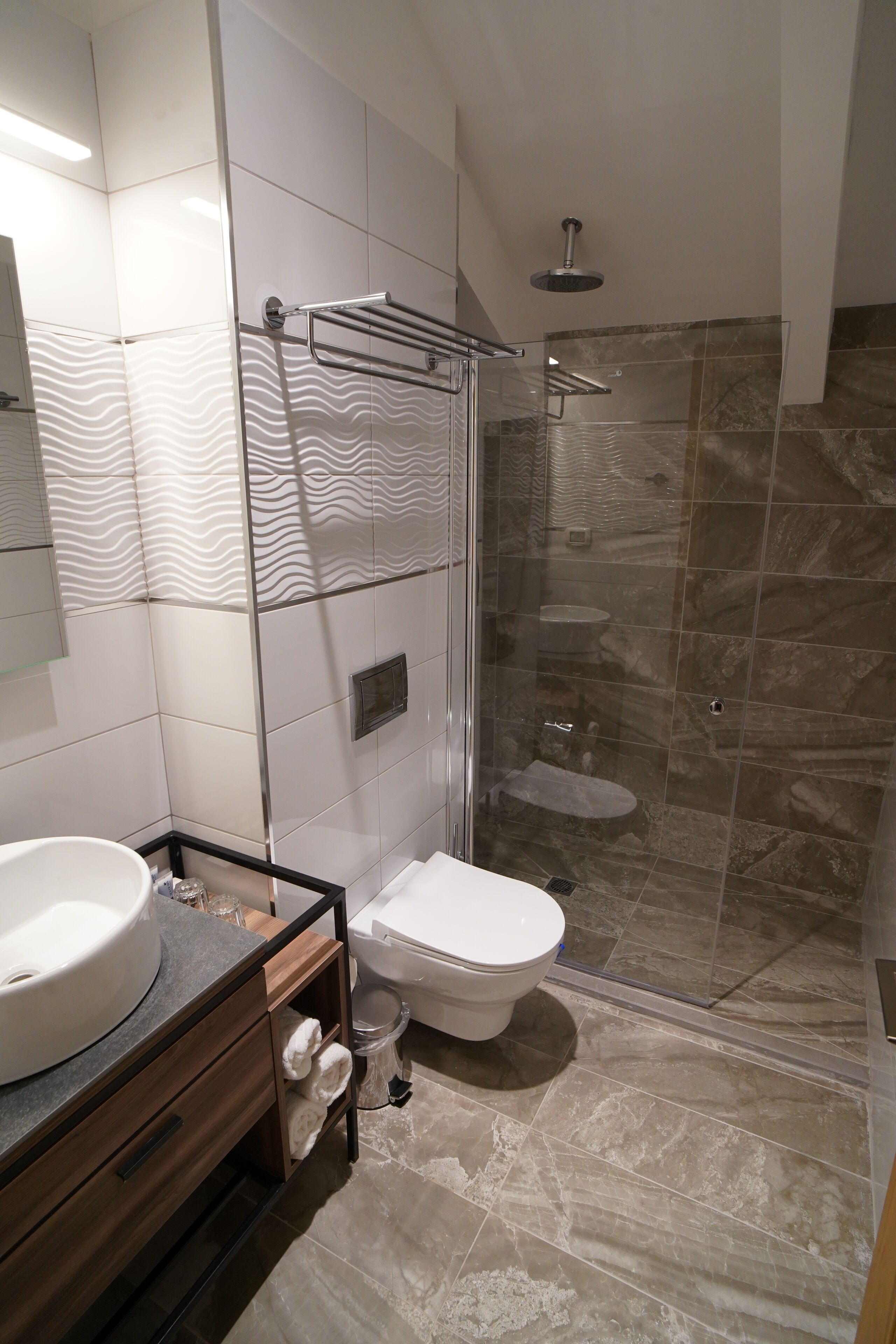 Un bagno moderno con box doccia in vetro, un lavandino bianco e un water.