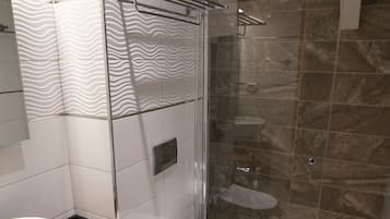 Un bagno moderno con box doccia in vetro, un lavandino bianco e un water.