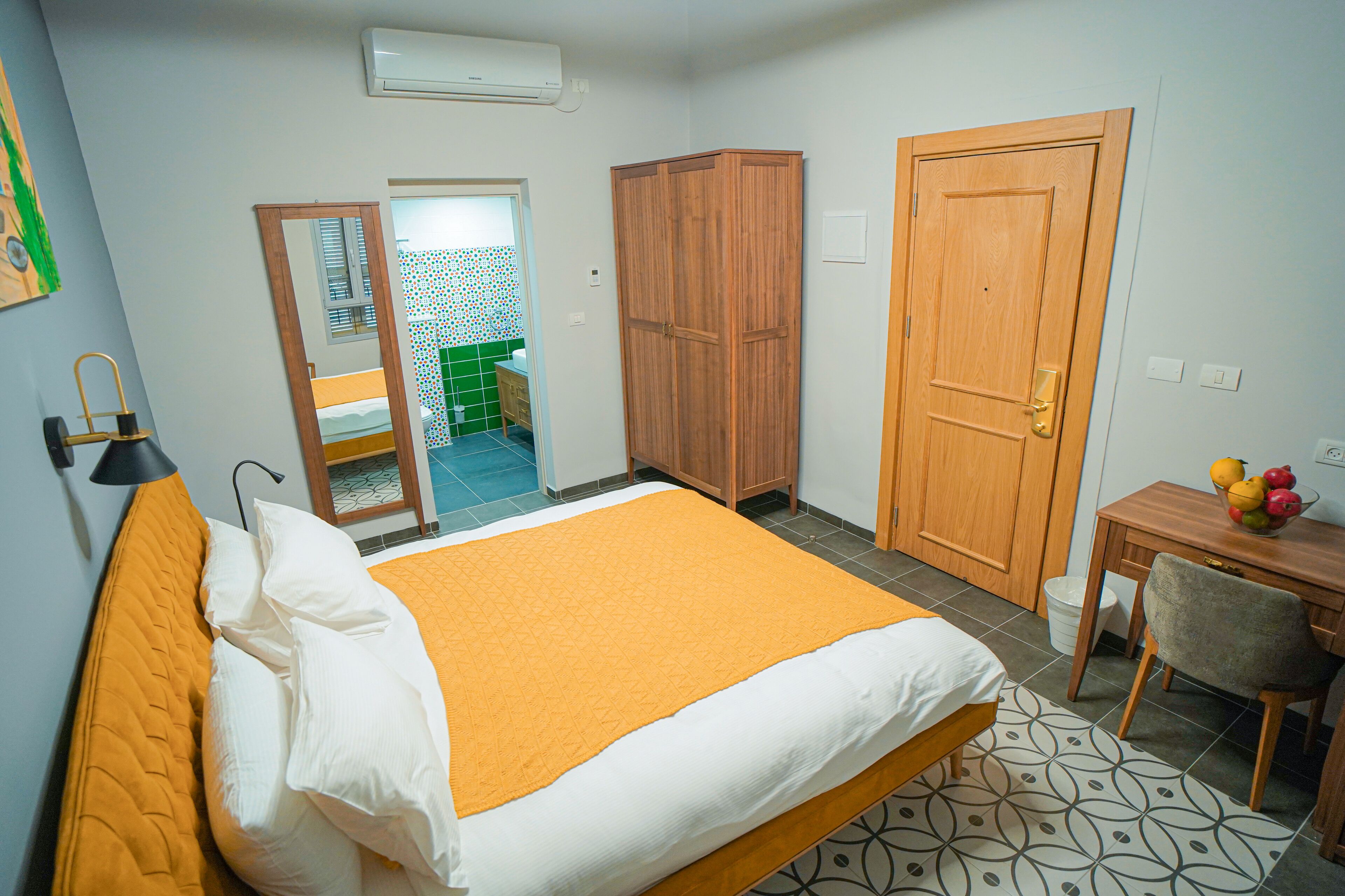 A bedroom with a bed, wardrobe, and a small table with fruit.
