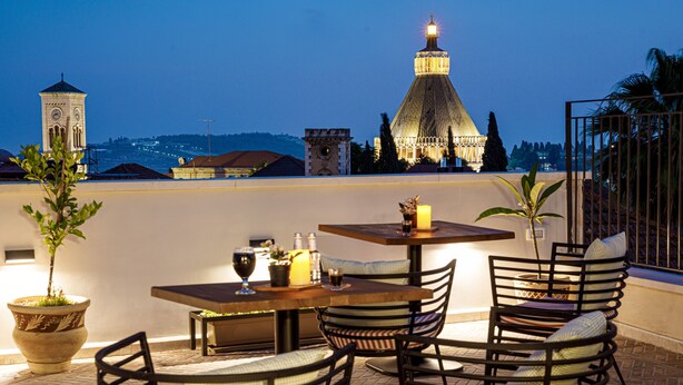 An outdoor dining area with a view of a historic building and a tower. - Michel House (Nazareth)