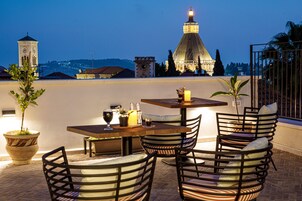 An outdoor dining area with a view of a historic building and a tower.