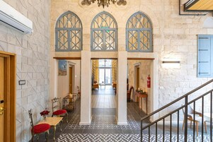 A hotel lobby with a geometric patterned floor, a staircase, and a view into the dining area.