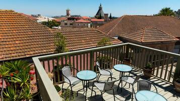 Terraço no telhado com área de estar externa e vista panorâmica da cidade.