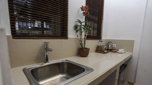 A kitchen with a stainless steel sink, a potted plant, and a coffee maker on the counter. - Jati Cottage (Ubud)