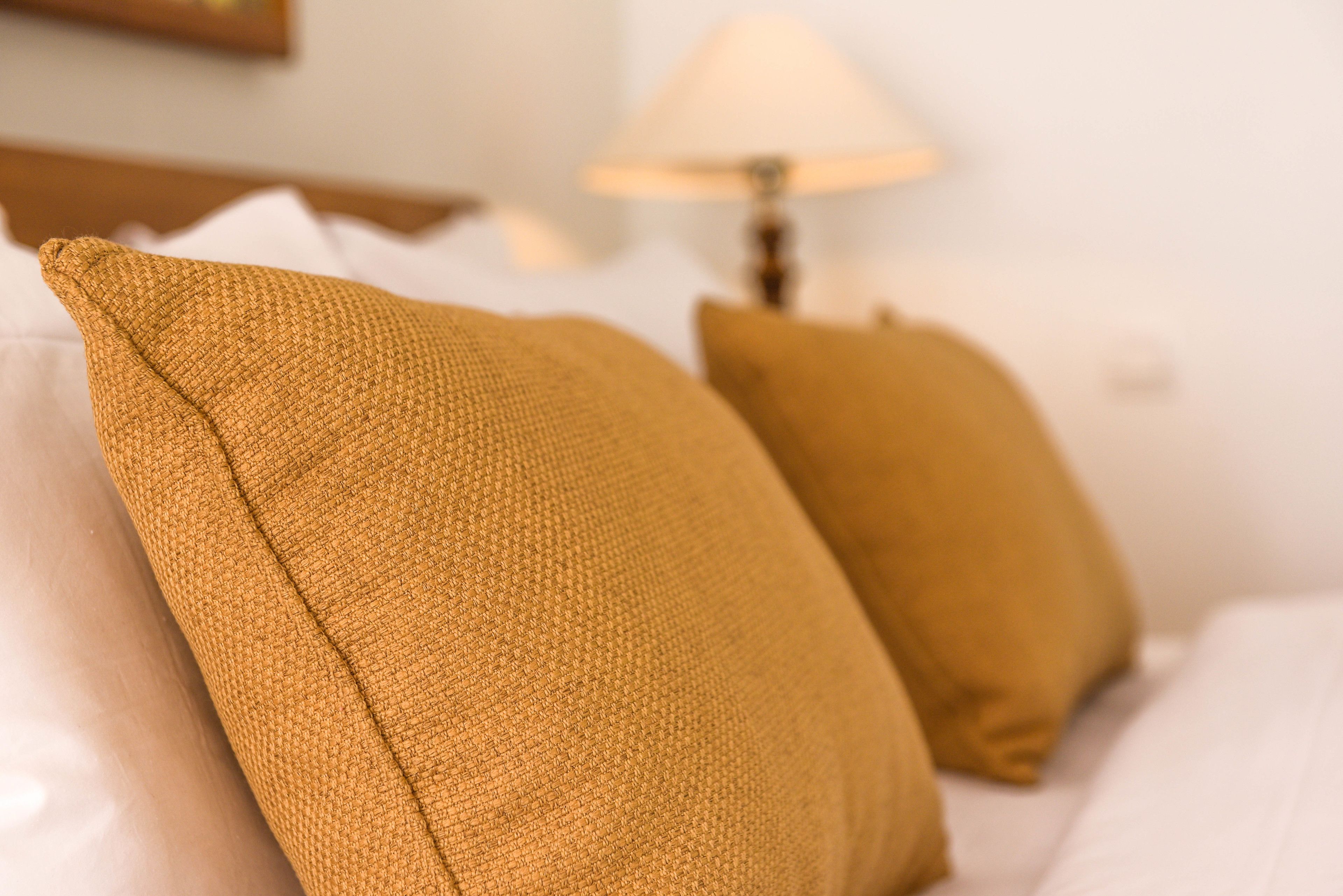A close-up of two mustard-colored pillows on a bed.