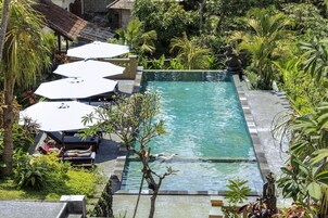 Una piscina al aire libre, sombrillas, sillones reclinables de piscina