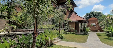 A well-maintained garden with a pathway leading to a building with a tiled roof and a traditional architectural style.
