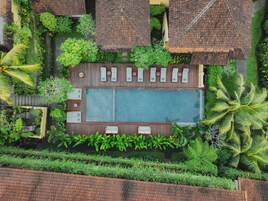 Una piscina al aire libre, sombrillas, sillones reclinables de piscina