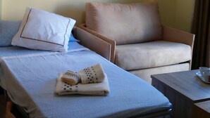 A hotel room with two beds, a chair, a small table, and a lamp. - Apartamentos Turísticos La Garza (Cáceres)