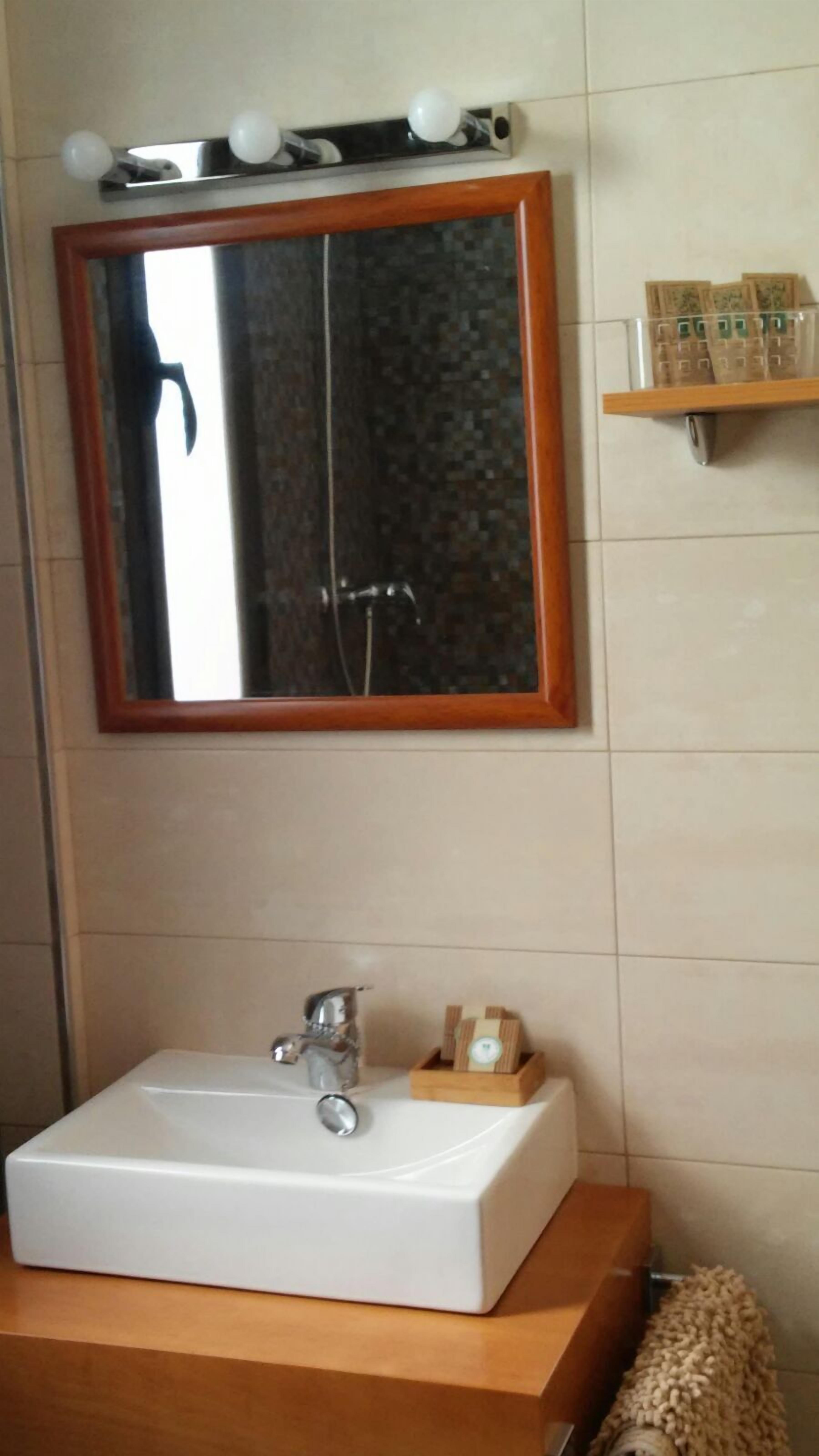 A bathroom with a white sink, a wooden vanity, a mirror with a wooden frame, and a towel rack with a towel.
