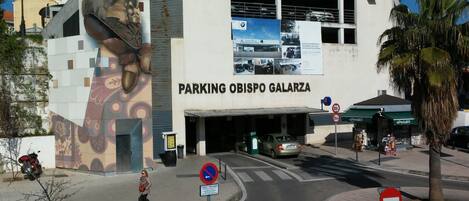 Un edificio con un mural grande, la entrada de un estacionamiento y un letrero de restaurante.
