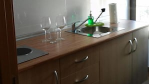 A kitchen with a wooden countertop, a stainless steel sink, and a green soap dispenser. There are two wine glasses on the counter. - Apartamentos Turísticos La Garza (Cáceres)
