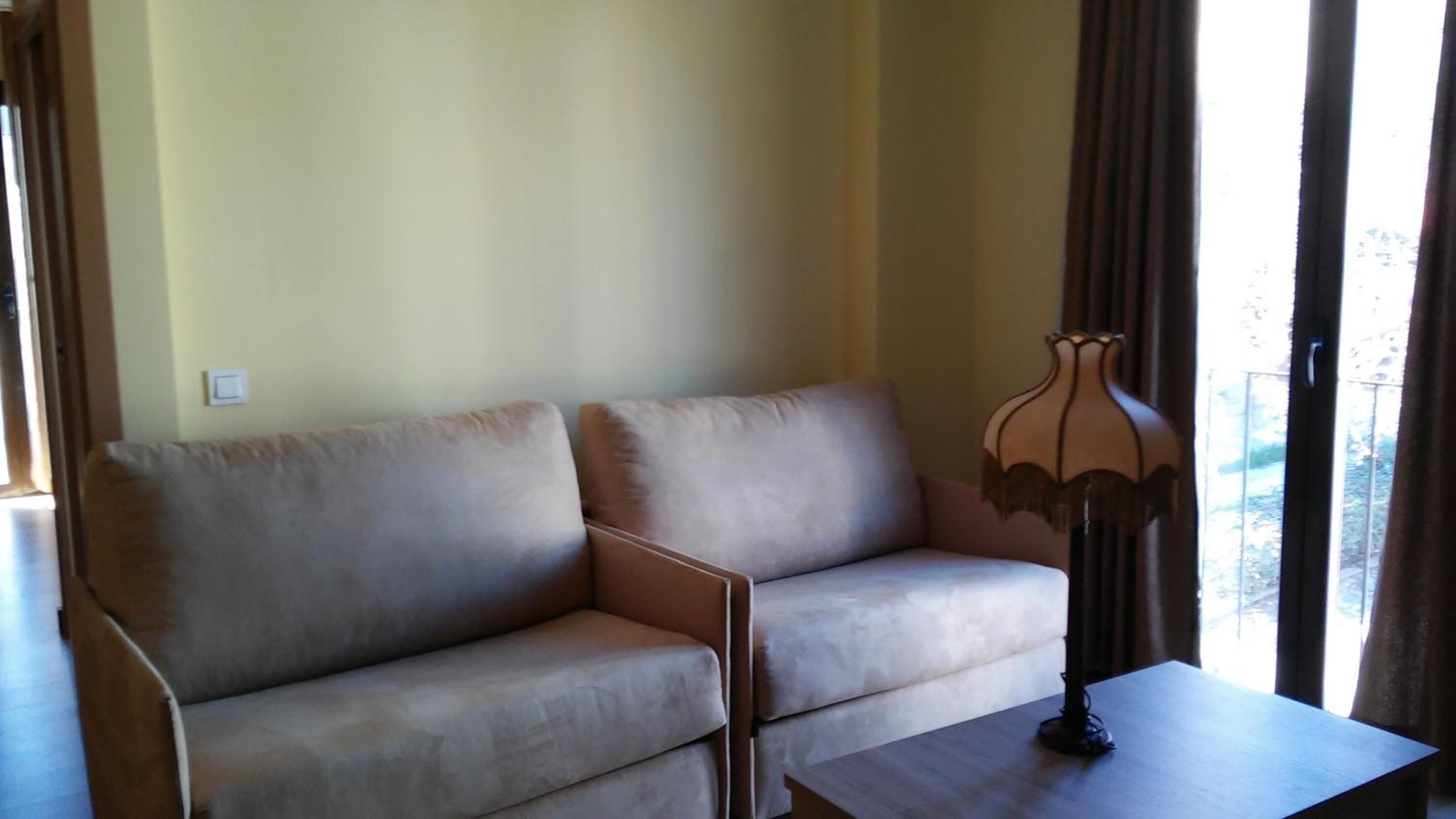 Un salon avec un canapé beige, une petite table et une lampe.