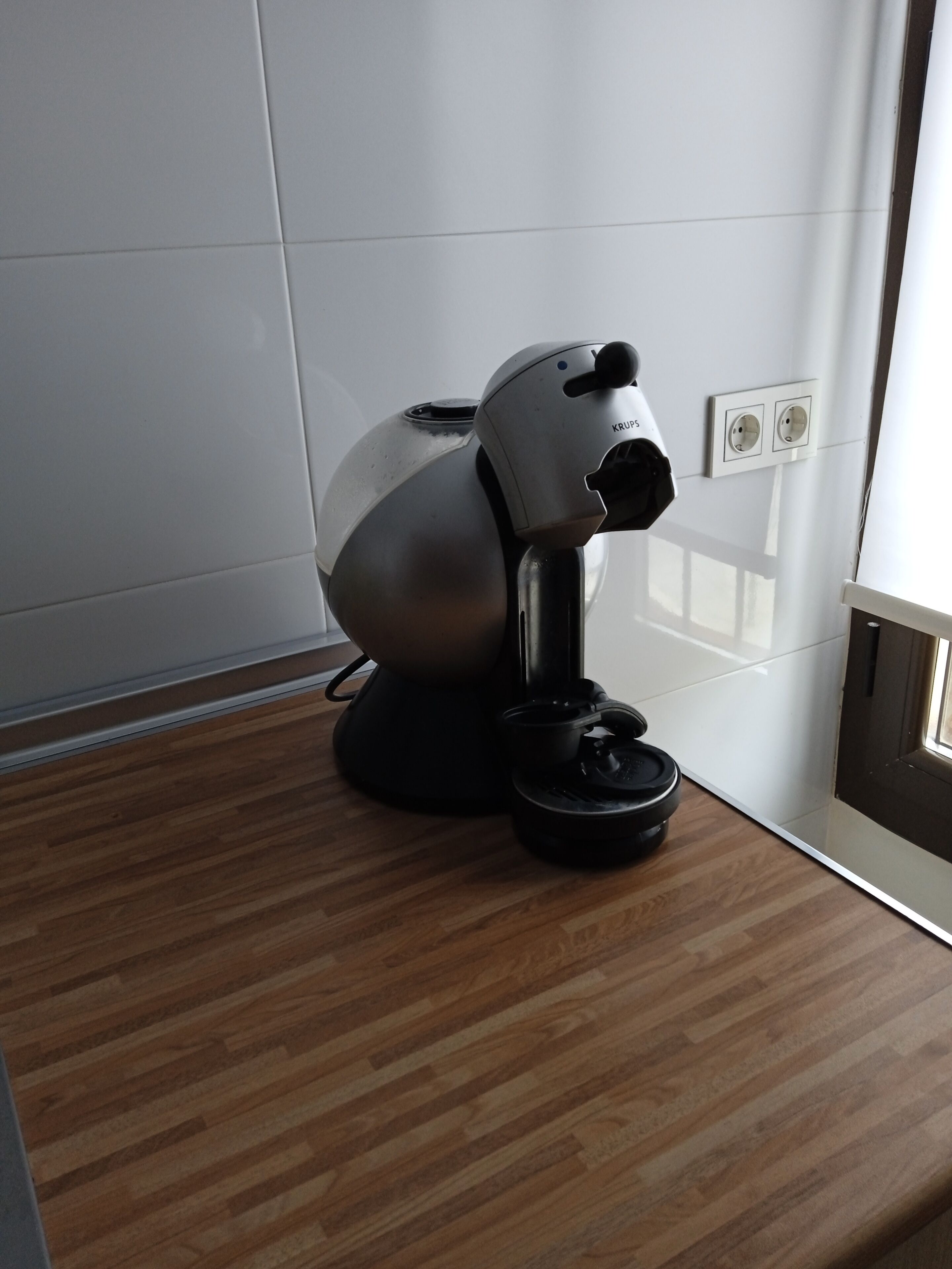 Una habitación moderna con suelo de madera, pared blanca y un dispositivo montado en el techo.