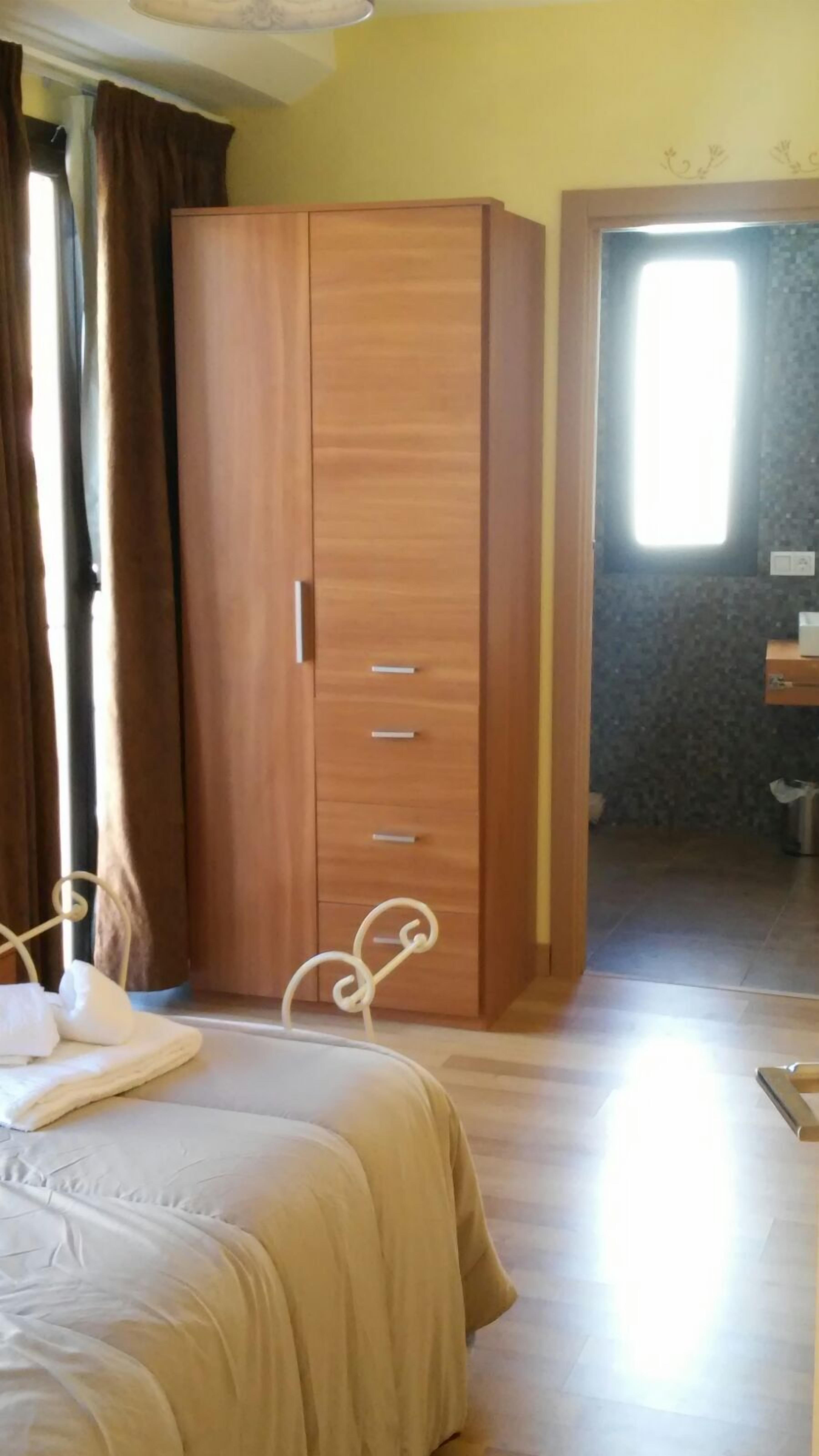 A bedroom with a bed, a wardrobe, and a bathroom visible through an open door.