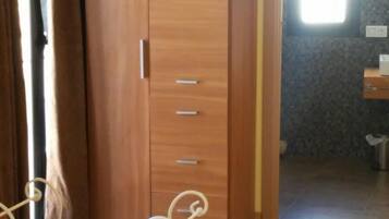 A bedroom with a bed, a wardrobe, and a bathroom visible through an open door.
