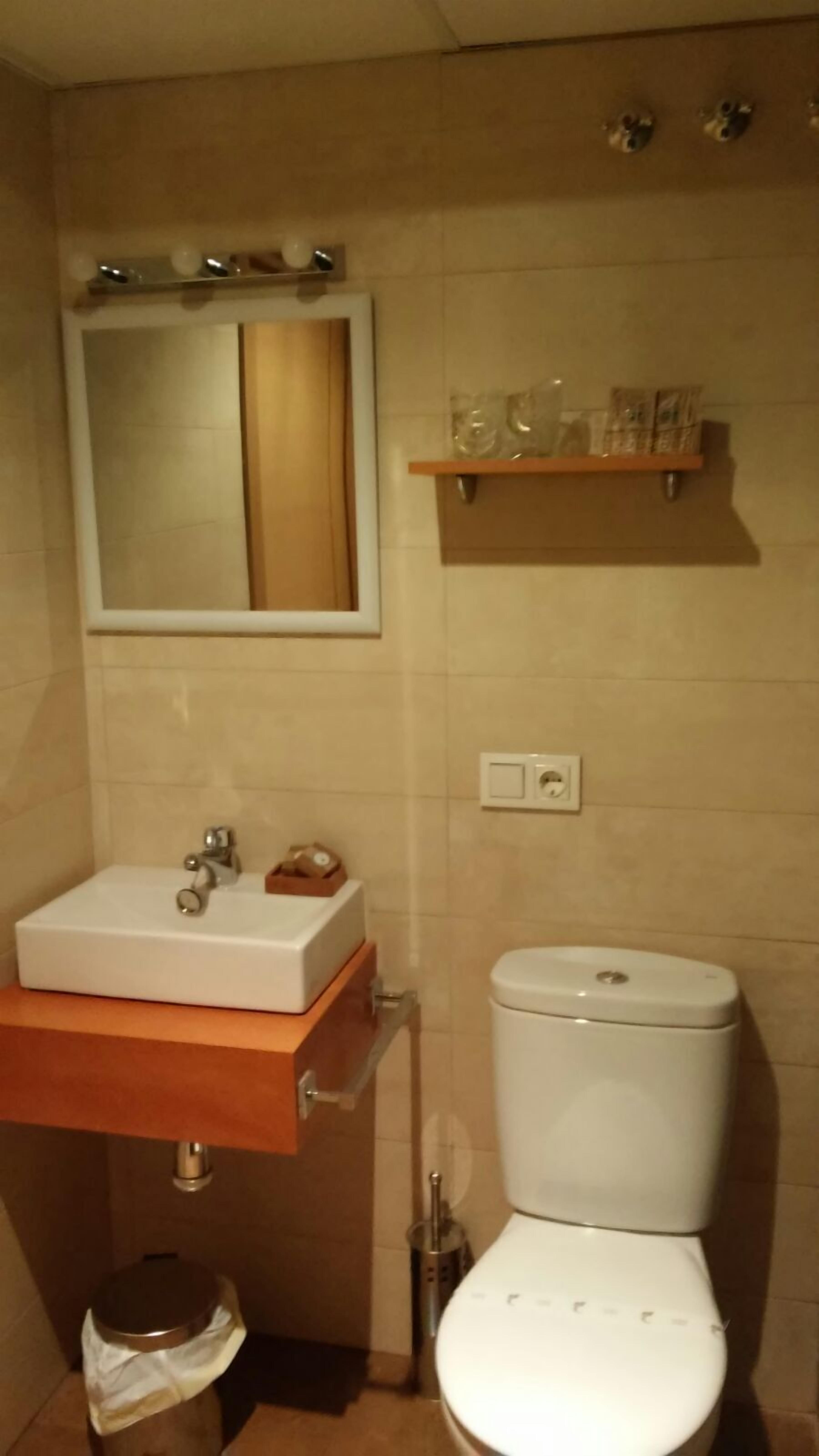 Un baño con lavamanos, espejo y retrete blancos.