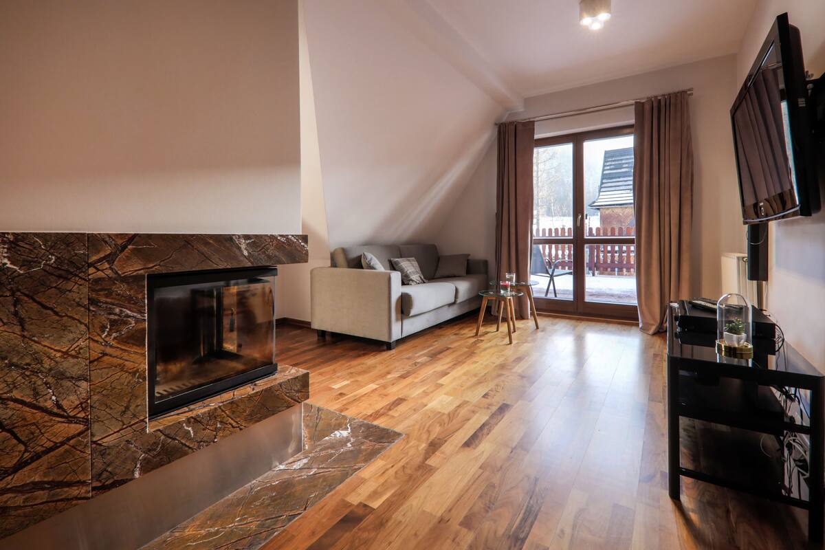 A modern living room with a stone fireplace, a sofa, and a television.